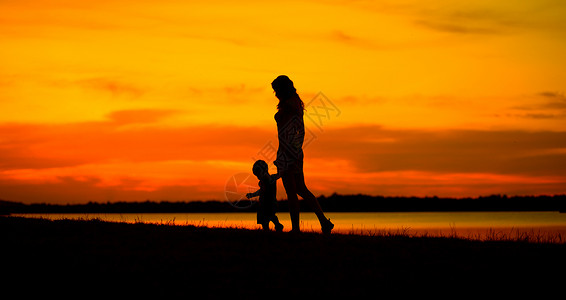 令人愉快的看母亲带着孩子看着美丽的日落背景