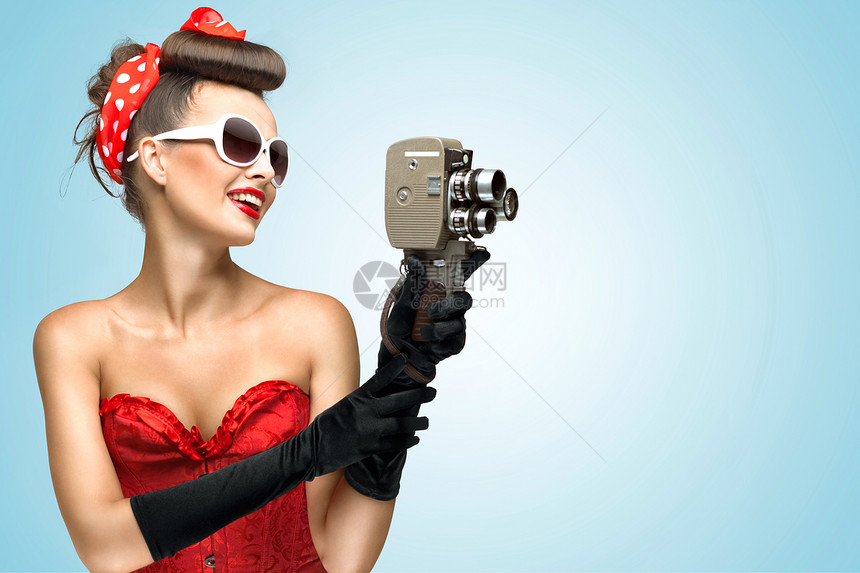 紧身胸衣手套的女孩的照片,拿着老式的8毫米相机图片