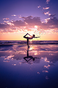 水平衡日落时海滩上练瑜伽的女人的剪影背景