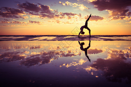 日落时海滩上练瑜伽的女人的剪影高清图片