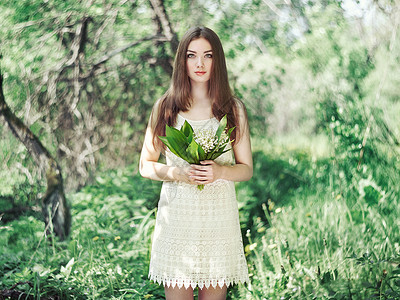 美丽的轻女子与百合花的山谷肖像关于自然的女孩春天的花朵时尚美背景图片
