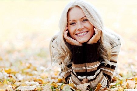 美丽的微笑的女人躺干燥的秋叶上秋天树叶上的女人图片