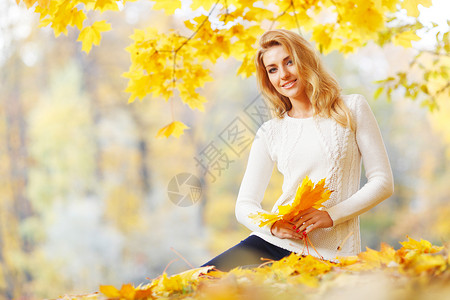 离堆公园堆枫叶的女人快乐可爱的女人的肖像,手里着干燥的枫叶秋天的公园里背景