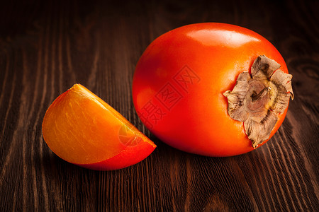 新鲜成熟的橙色柿子,木制背景上切片图片