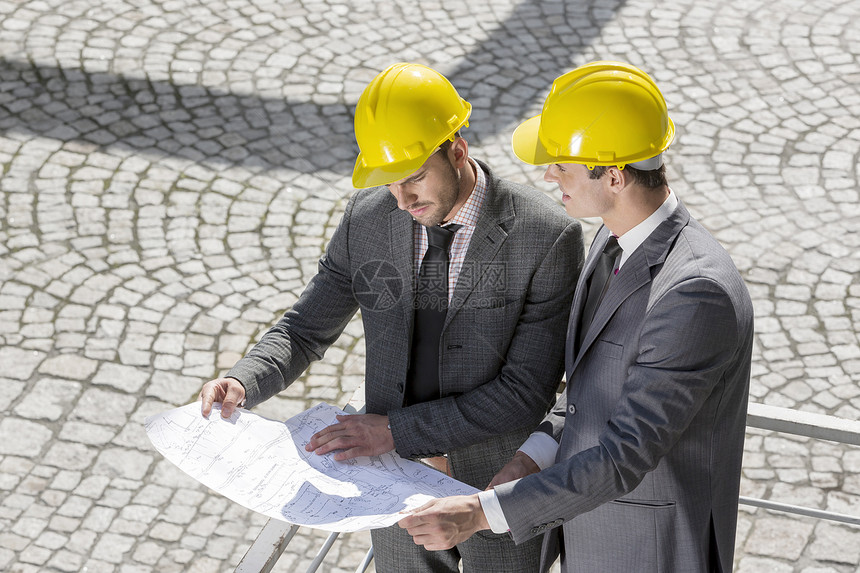 轻的男建筑师建筑工地分析蓝图图片