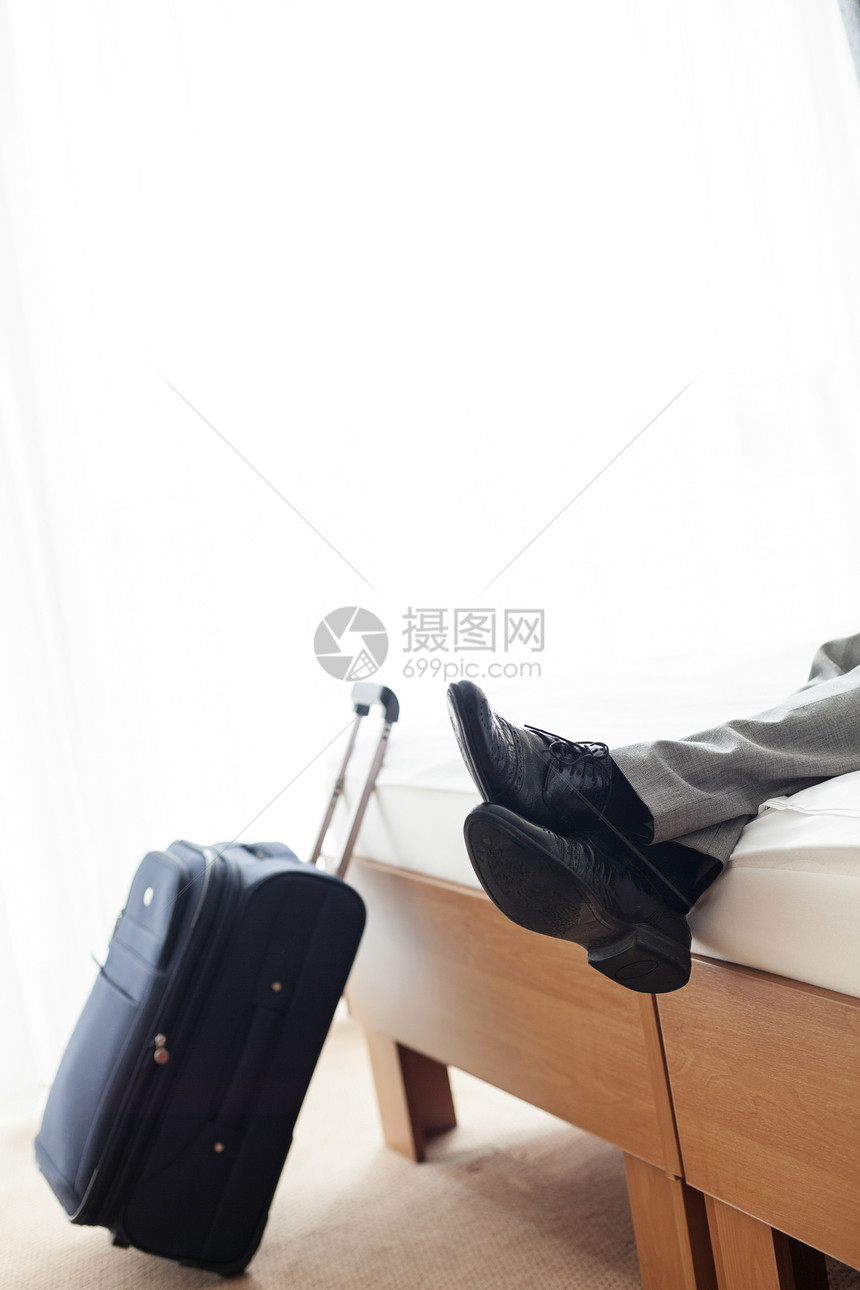 低段商人躺床上,酒店房间的行李旁边图片
