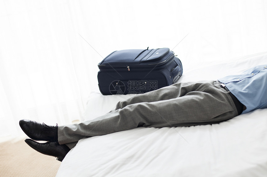 低段商人睡酒店房间的行李旁边图片