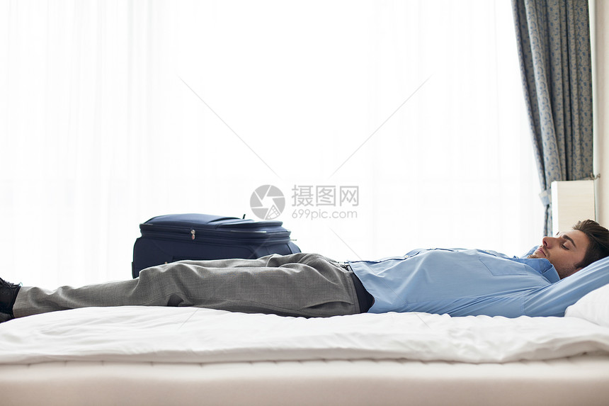 轻商人睡酒店房间的侧景图片