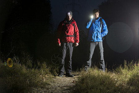 夜间野外用手电筒拍摄的男徒步旅行者的全长肖像背景图片