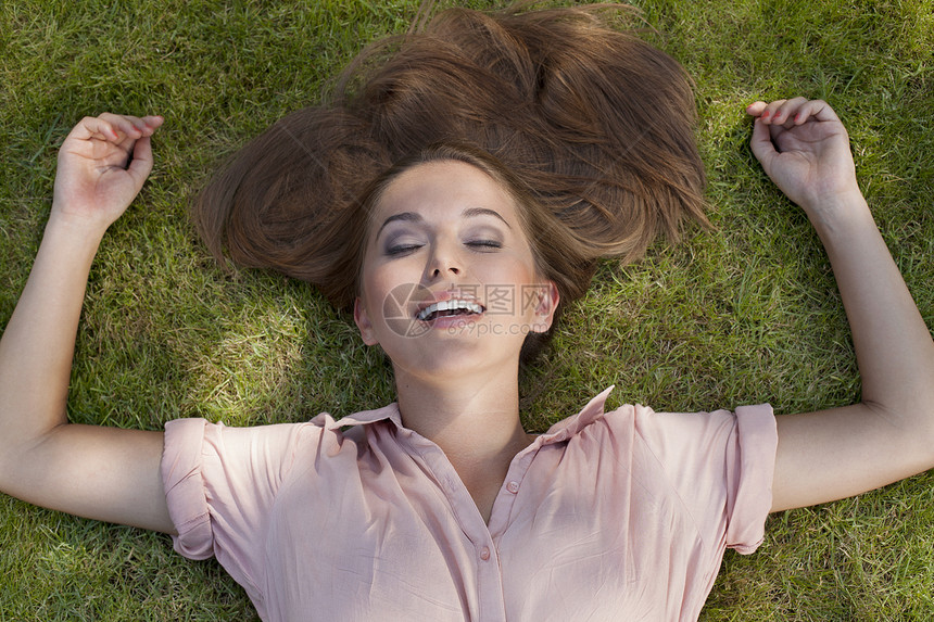放松的轻女人躺公园的草地上图片