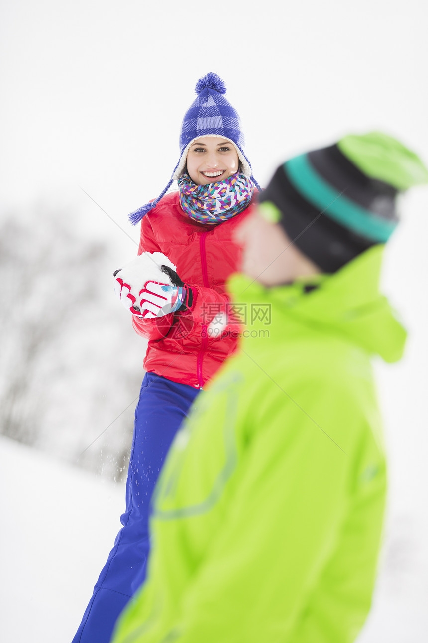 微笑的轻女人男朋友打雪仗图片