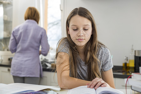 女孩桌子上学,母亲站后台背景图片