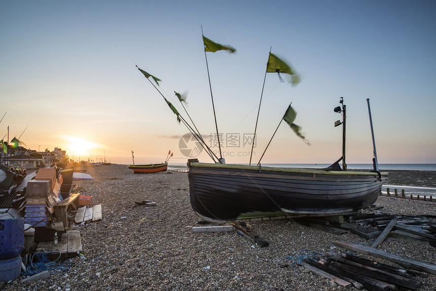 日出时海滩上小型渔船的景观形象图片