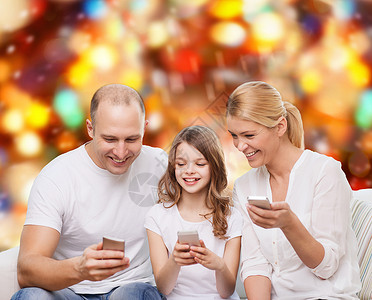 家庭,假期,技术人微笑的母亲,父亲小女孩与智能手机红灯背景图片