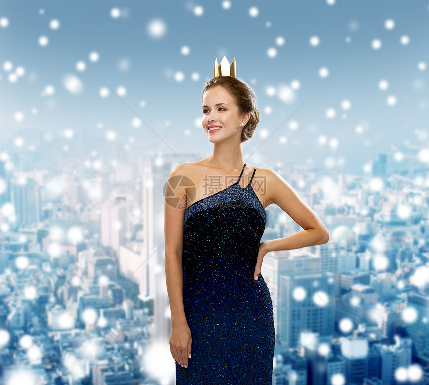 人们,节日,皇室诞节的微笑的女人穿着晚礼服,戴着金色的皇冠雪城的背景图片