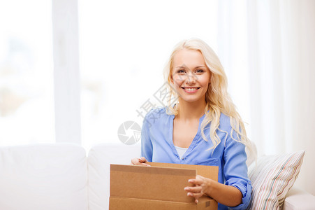 交通,邮政人的微笑的轻妇女打开纸板箱家里图片