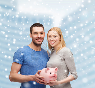 雪中女人金融,金钱,人家庭的微笑的夫妇持大储蓄罐雪城中心的背景设计图片