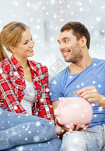金钱,家庭,金融关系的微笑的夫妇储蓄罐坐沙发上图片