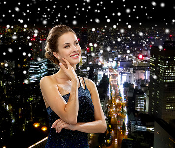 人,假日魅力微笑的女人晚礼服黑色背景下雪夜城市背景图片