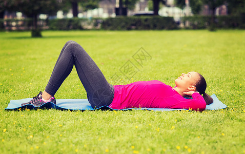 健身,运动,训练,公园生活方式的微笑的女人户外垫子上运动图片