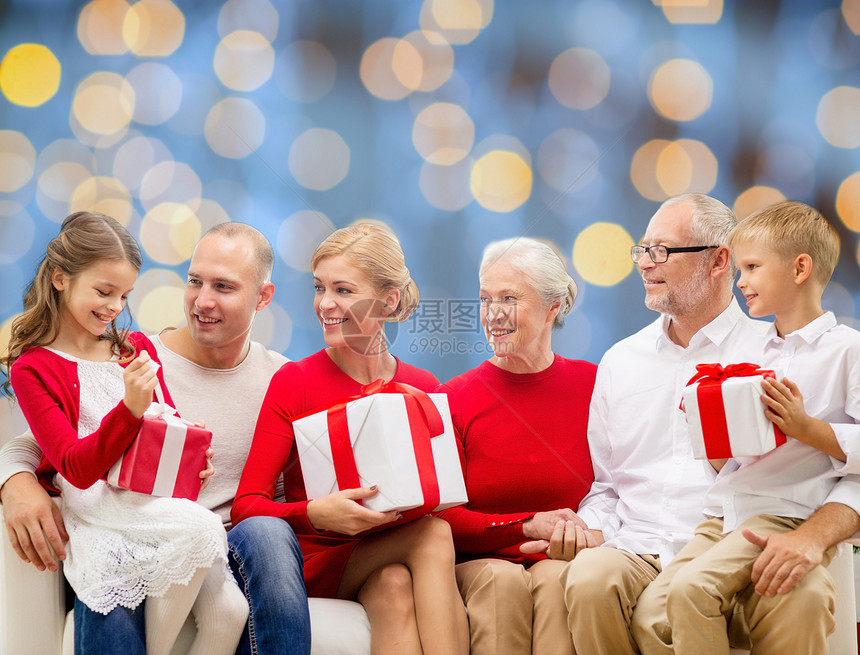 家庭,假日,代,诞节人们的微笑的家庭与礼品盒坐沙发上的蓝光背景图片