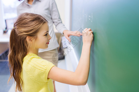 教育,小学,学,数学人的小微笑的女学生教室的绿色粉笔板上写数字图片