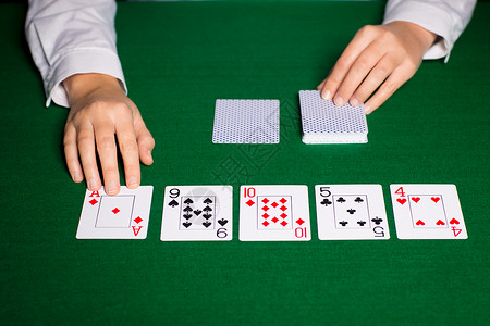 赌场,扑克,人娱乐活动的密切持经销商的手与扑克牌图片