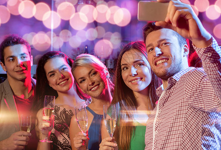 派,假期,技术,夜生活人们的微笑的朋友带着杯香槟智能手机俱乐部自拍图片