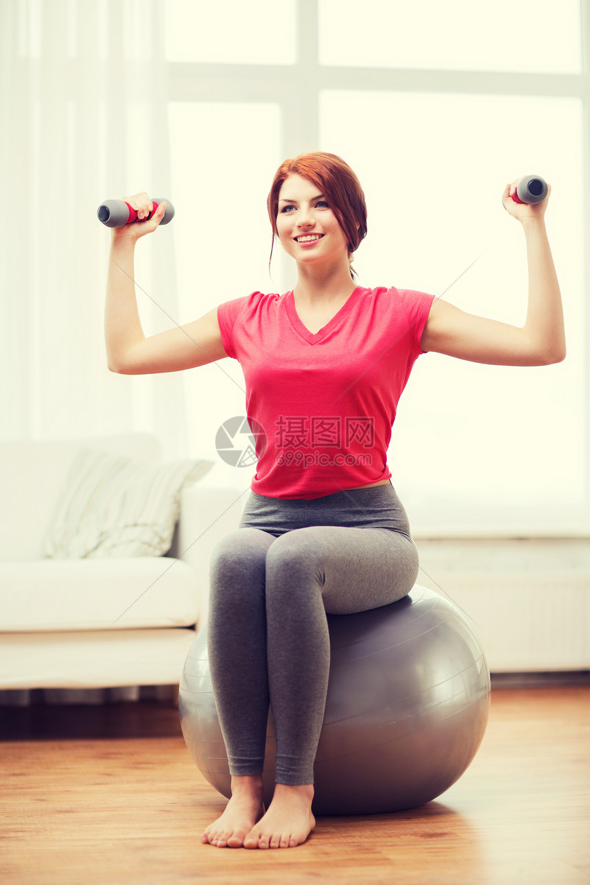 健身,家庭饮食微笑的红头发女孩锻炼与健身球哑铃家里图片