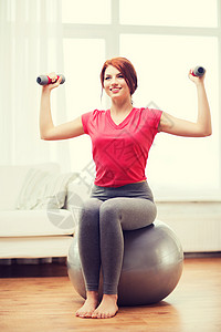 健身,家庭饮食微笑的红头发女孩锻炼与健身球哑铃家里图片