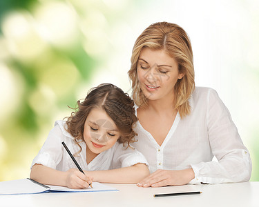 人家庭学校家庭教育育儿理念快乐的母亲女儿绿色背景下作业笔记本上写作图片