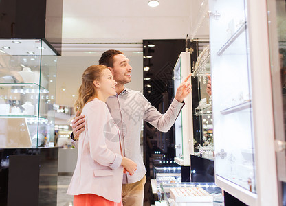 销售,消费主义人们的幸福的夫妇指着购物窗口商场的珠宝店图片