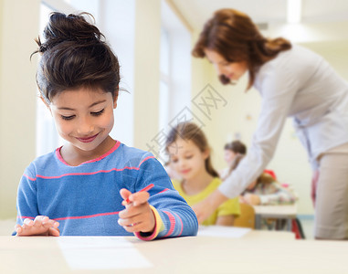教育,小学儿童快乐的小学生女孩,用笔纸写作,课堂教师背景下图片
