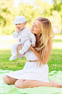 家庭孩子父母的快乐的母亲小婴儿坐公园的毯子上图片