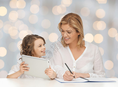 人,家庭,家庭教育,儿童技术快乐的母亲女儿与平板电脑笔记本电脑假日灯光背景图片