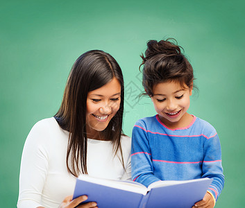 家庭,孩子,教育,学校快乐的人的快乐的老师小女孩阅读书的绿色粉笔板背景图片