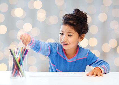 孩子,创造力快乐的人的快乐的小女孩用彩色铅笔假日灯光背景上画画图片