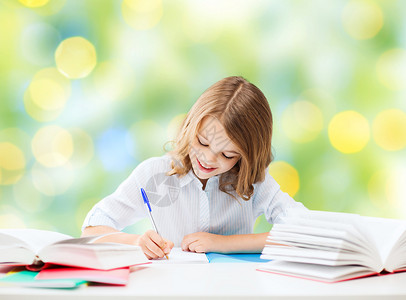 教育,人,孩子学校的快乐的学生女孩坐桌子上,着书,绿灯背景下写笔记本上图片