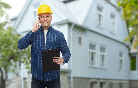 维修,建筑,房地产维修微笑的人建筑工人头盔与剪贴板调用智能手机客厅背景背景