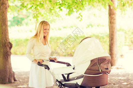 家庭,孩子父母的快乐的母亲与婴儿车公园图片