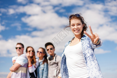 暑假青少十几岁的女孩戴着太阳镜朋友外闲逛,竖大拇指带耳机的十几岁女孩外的朋友背景图片