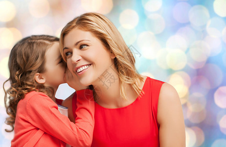 人,母亲,家庭收养的快乐的母亲女儿蓝色的节日灯光背景上低声耳语图片