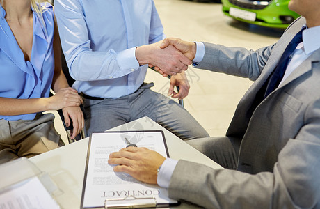 汽车推销员汽车业务,汽车销售,手势人的密切客户与经销商握手车展沙龙背景