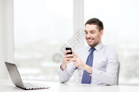 商业,办公室技术微笑的商人与笔记本电脑智能手机办公室图片