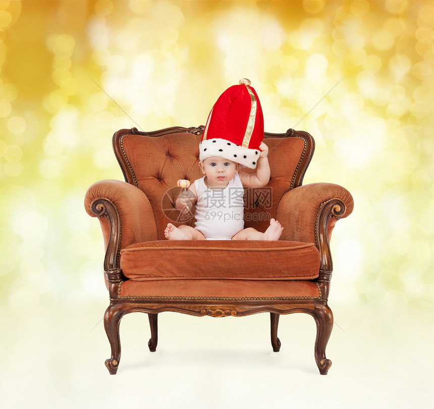 人,童,假日皇室快乐的男孩戴着皇家帽子,棒棒糖坐椅子上的黄色灯光背景图片