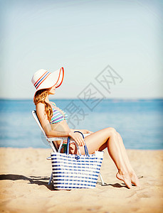 暑假假期女孩海滩椅子上晒太阳背景图片