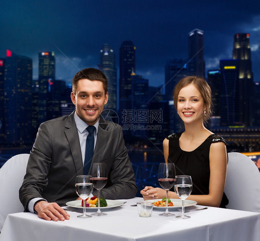 人们,庆祝,浪漫假期的微笑的夫妇吃主菜与红酒餐厅夜间城市背景图片