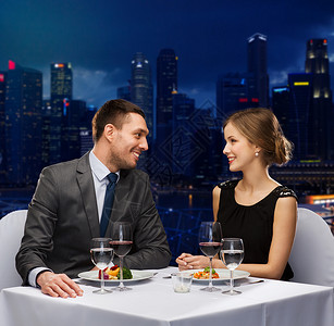 人们,庆祝,浪漫假日的微笑的夫妇与红酒食物餐厅交谈的夜晚城市背景图片