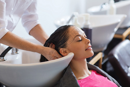 美容人的快乐的轻女人与理发师美发厅洗头背景图片