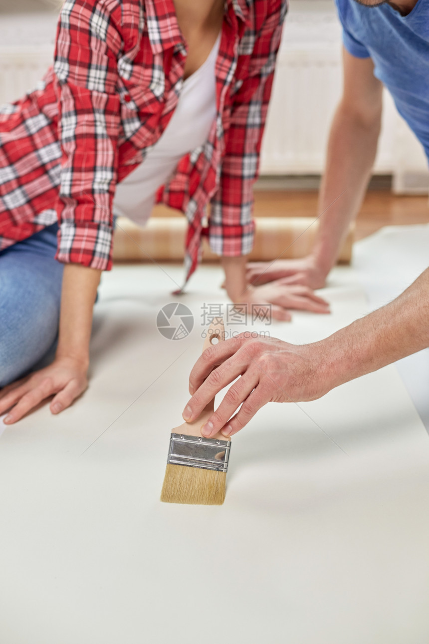 维修,翻新,建筑人的夫妇涂抹壁纸与胶水地板家里图片